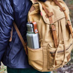 Sac à dos beige avec gourde en métal.
