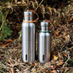 Deux gourdes inox posées sur l’herbe sèche