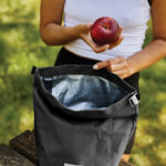 Personne tenant une pomme devant un sac isotherme.