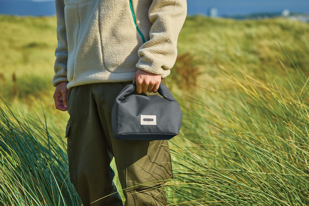 Personne tenant un petit sac noir en plein air