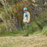 Personne debout sur une plage rocheuse et herbeuse