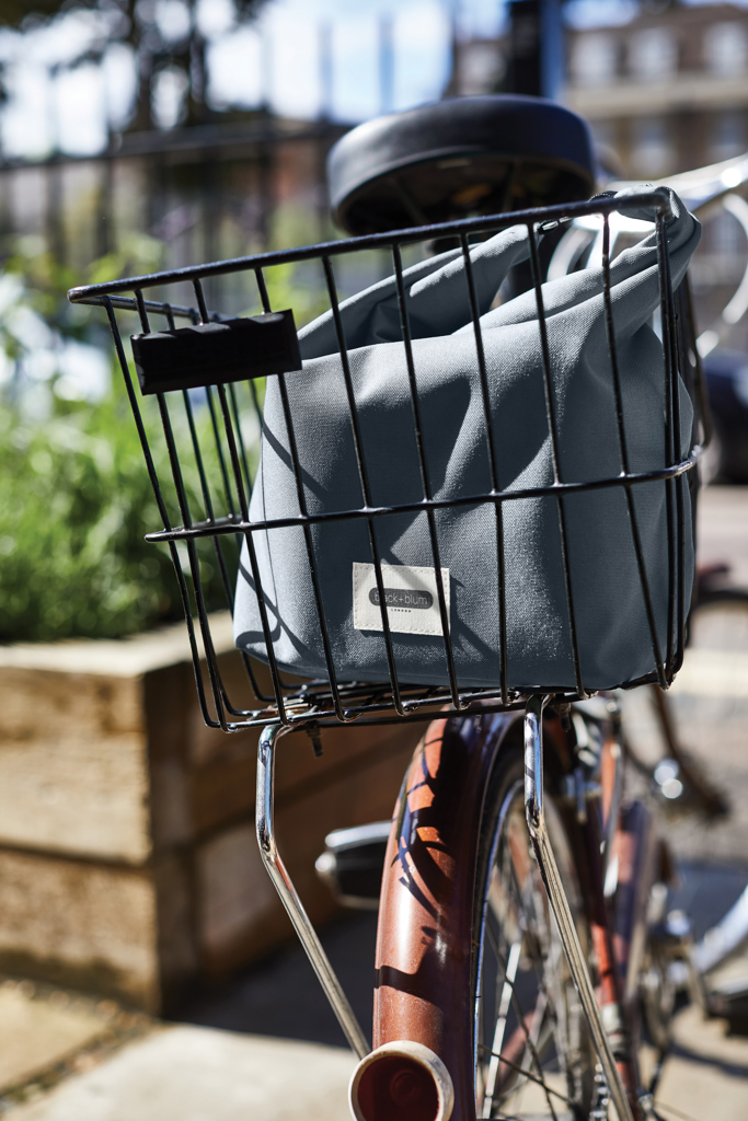 Sac gris dans panier arrière de vélo.