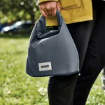 Personne tenant un sac gris dans un parc