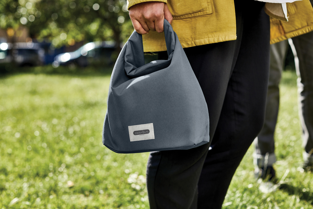 Personne tenant un sac gris dans un parc