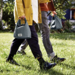 Deux personnes marchent avec des sacs gris.