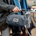 Sac gris suspendu au guidon d’un vélo.