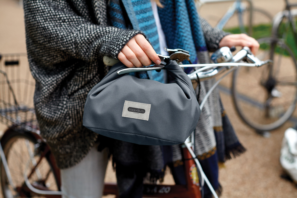 Sac gris suspendu au guidon d’un vélo.