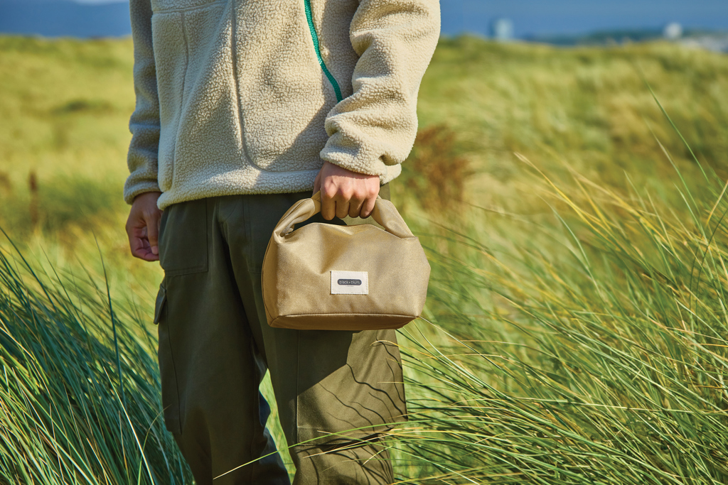 Personne tenant un sac beige dans la nature