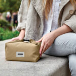 Personne tenant un sac repas beige dehors