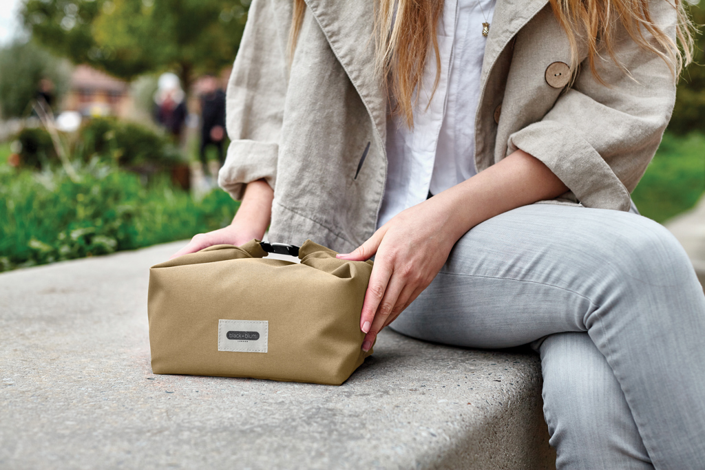 Personne tenant un sac repas beige dehors