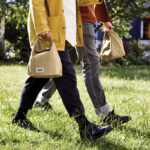 Deux personnes marchent avec des sacs beige.