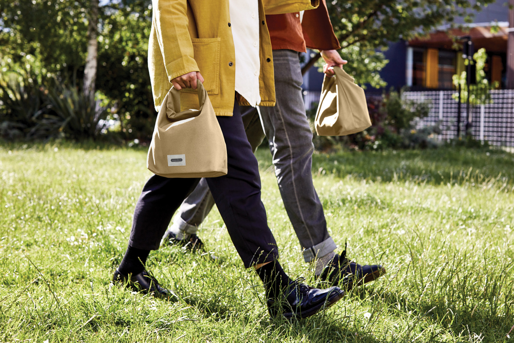 Deux personnes marchent avec des sacs beige.