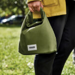 Personne tenant un sac repas vert en tissu.