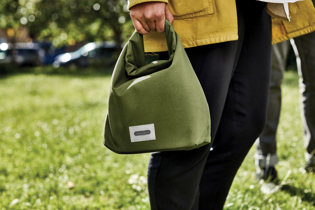 Personne tenant un sac repas vert en tissu.