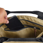 Main mettant un smartphone dans un sac beige