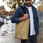 Homme portant un grand sac beige en ville