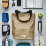 Objets de quotidien organisés autour d’un sac beige.