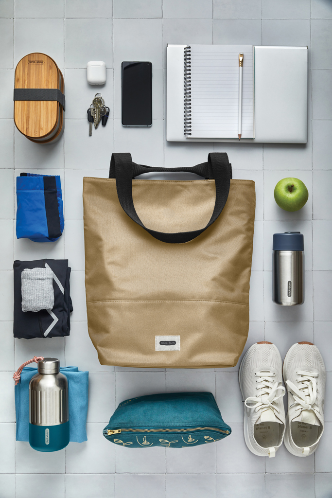 Objets de quotidien organisés autour d’un sac beige.
