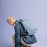 Personne accroupie portant un sac à dos bleu.