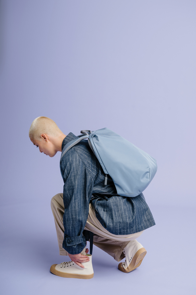 Personne accroupie portant un sac à dos bleu.
