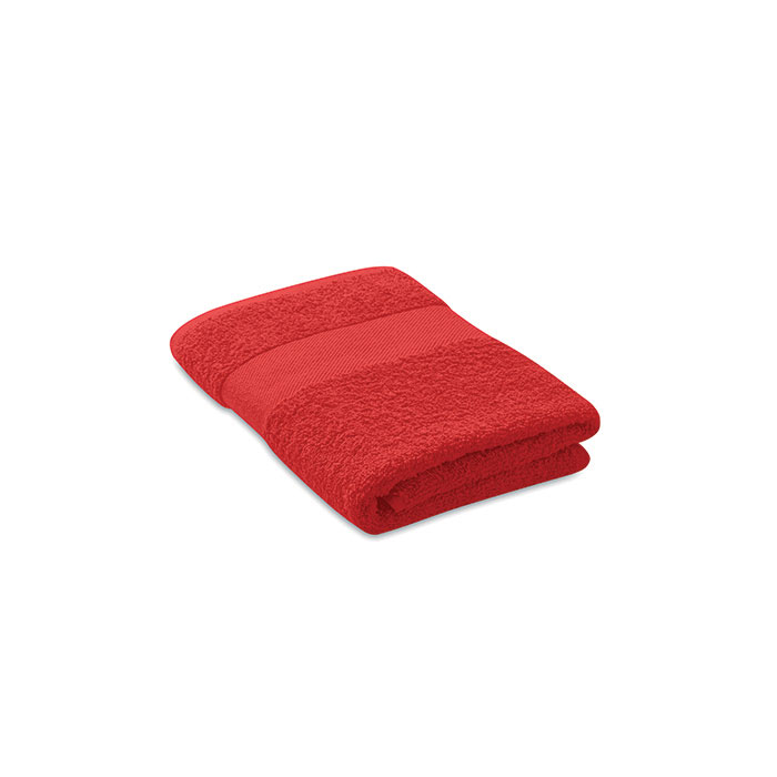 Serviette de bain rouge pliée sur fond blanc