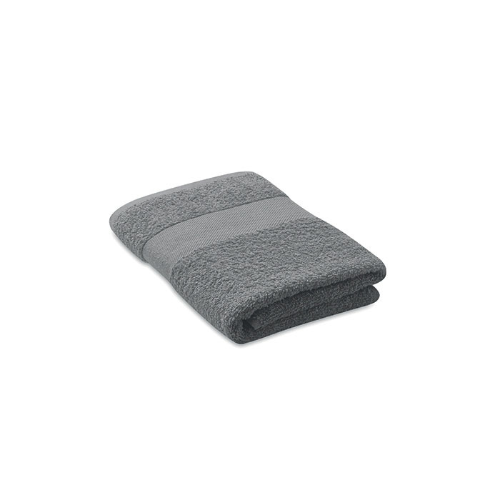 Serviette de bain grise pliée sur fond blanc