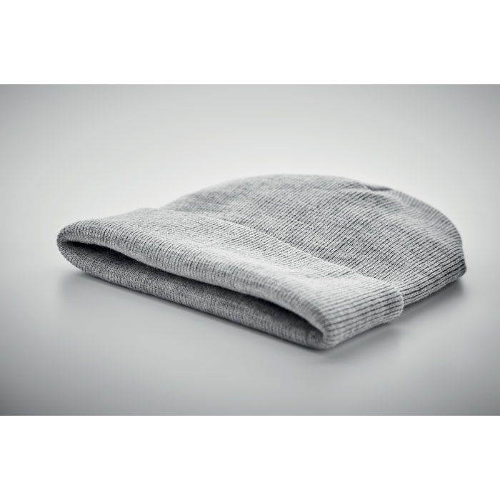 Bonnet gris en maille plié sur surface grise