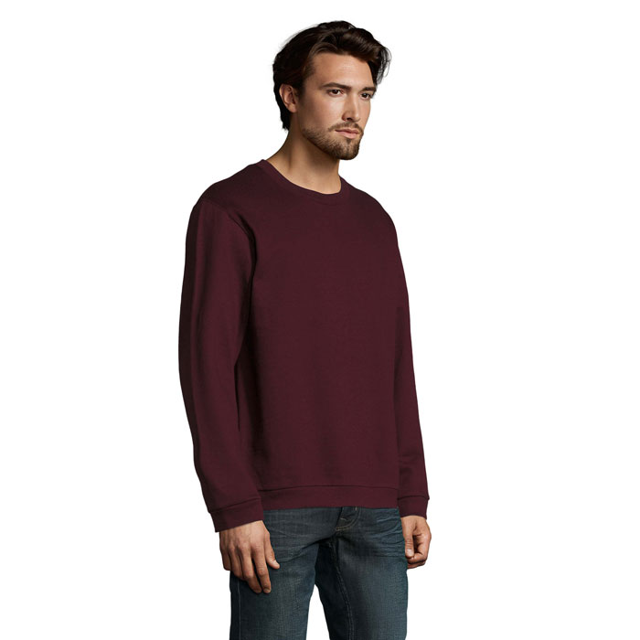 Homme portant un sweat bordeaux et un jean