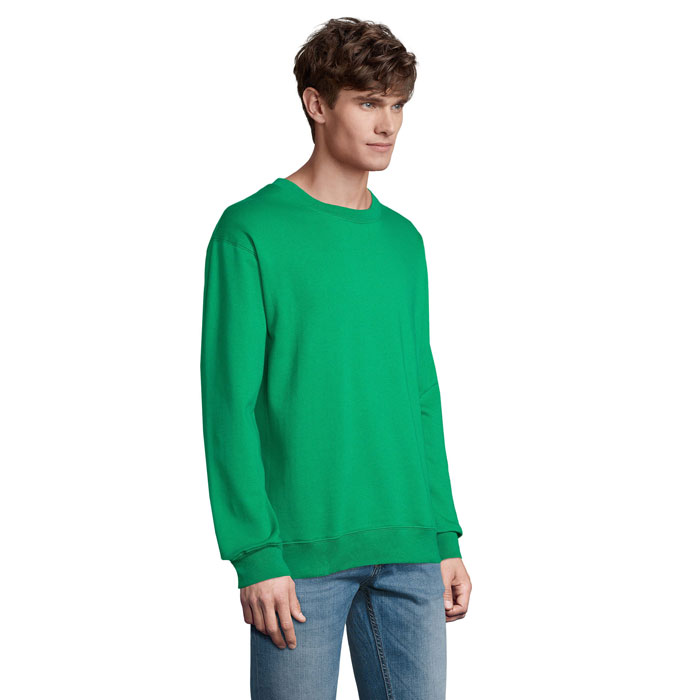 Homme portant un sweat vert et un jean.