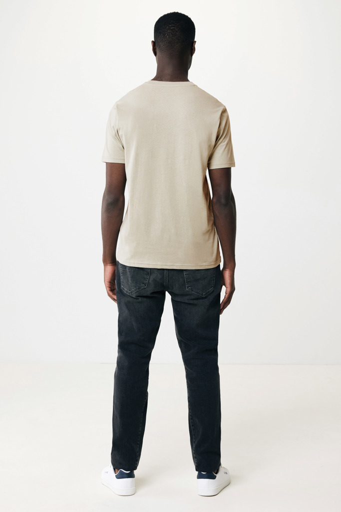 Homme portant t-shirt beige et jean noir.