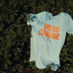 T-shirt bleu clair avec texte orange sur herbe