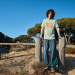 Homme debout portant un t-shirt sur plage ensoleillée
