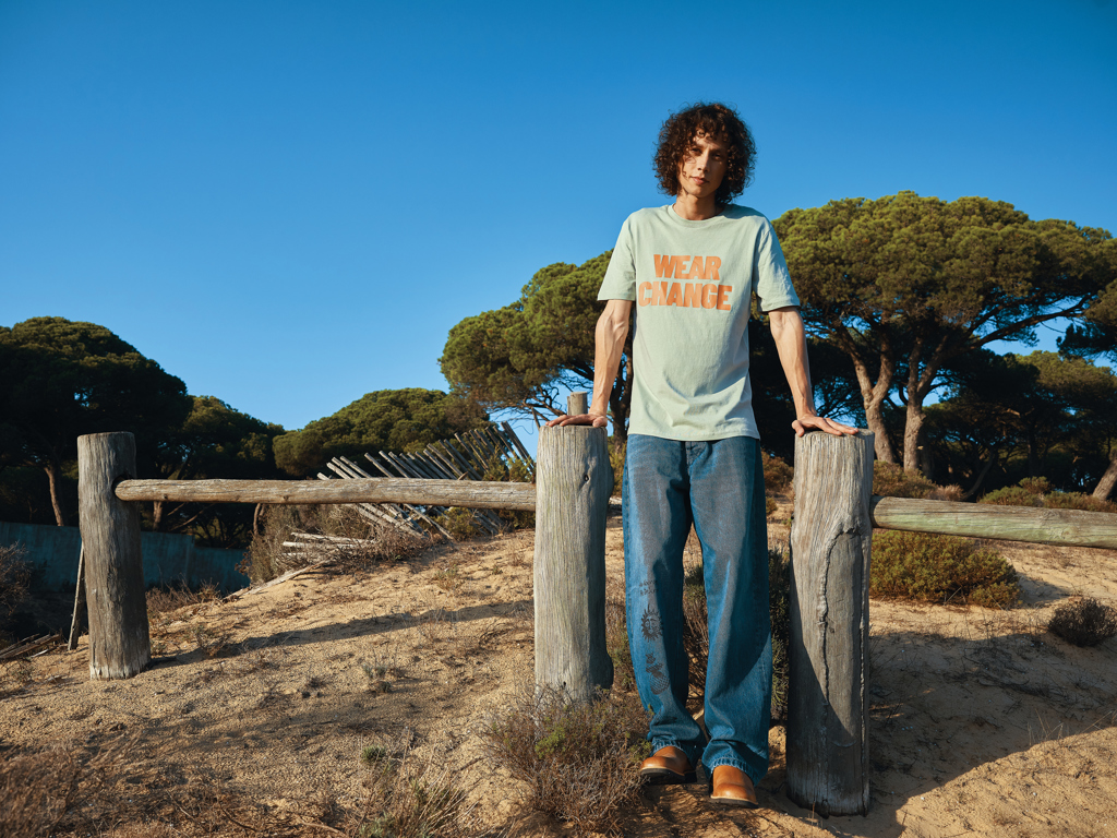 Homme debout portant un t-shirt sur plage ensoleillée
