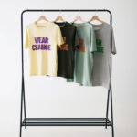 Quatre t-shirts colorés suspendus sur un portant.