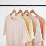 T-shirts pastel suspendus sur cintres en bois