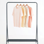 T-shirts pastel suspendus sur un portant noir