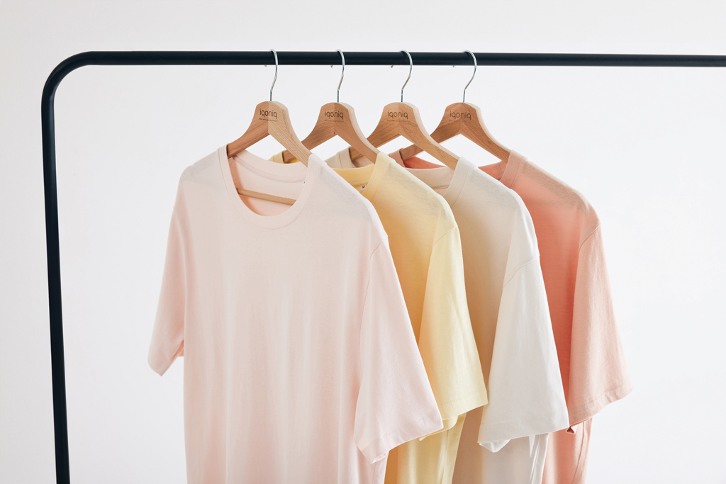 T-shirts pastel suspendus sur cintres en bois