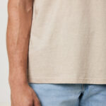 Main d’homme portant jean et t-shirt beige