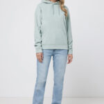 Femme portant un sweat vert et un jean.