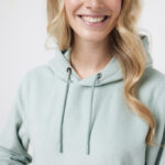 Femme souriante portant un sweat à capuche vert clair