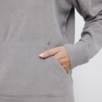 Main dans la poche d’un sweat gris