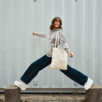 Personne souriante sautant avec un sac en toile