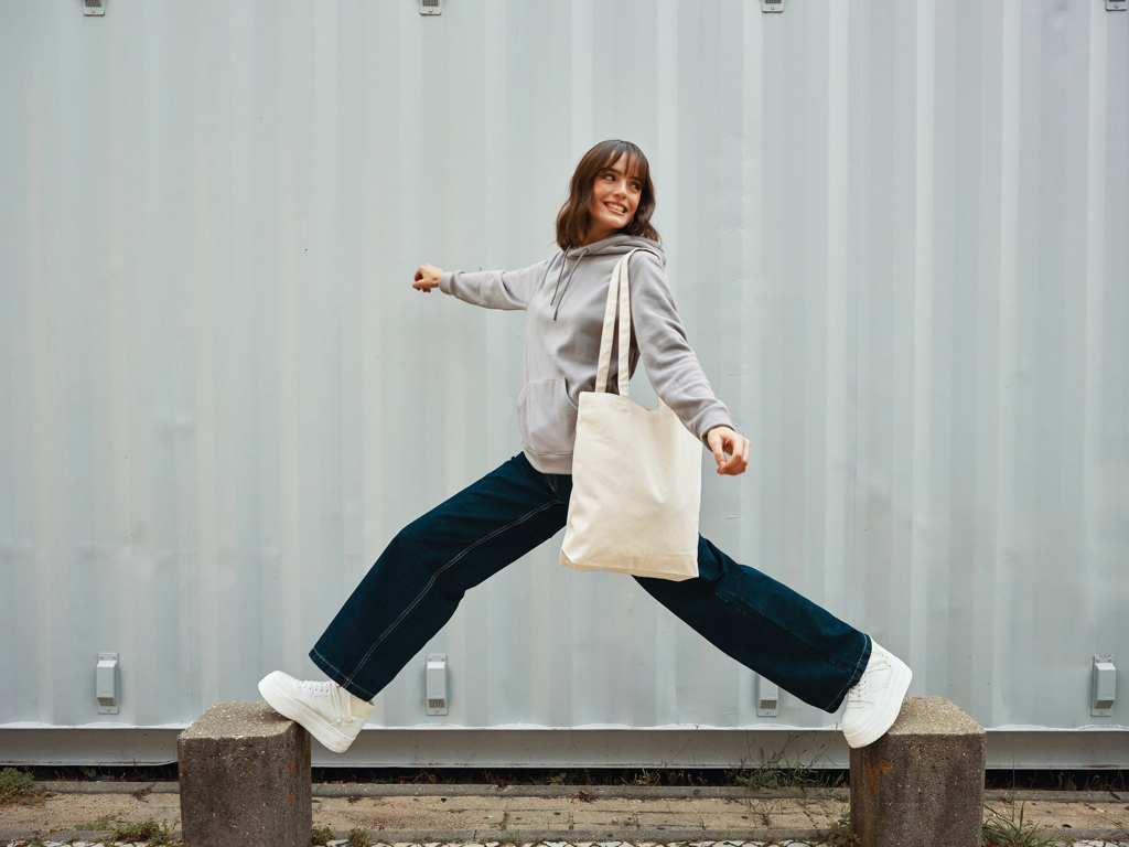 Personne souriante sautant avec un sac en toile