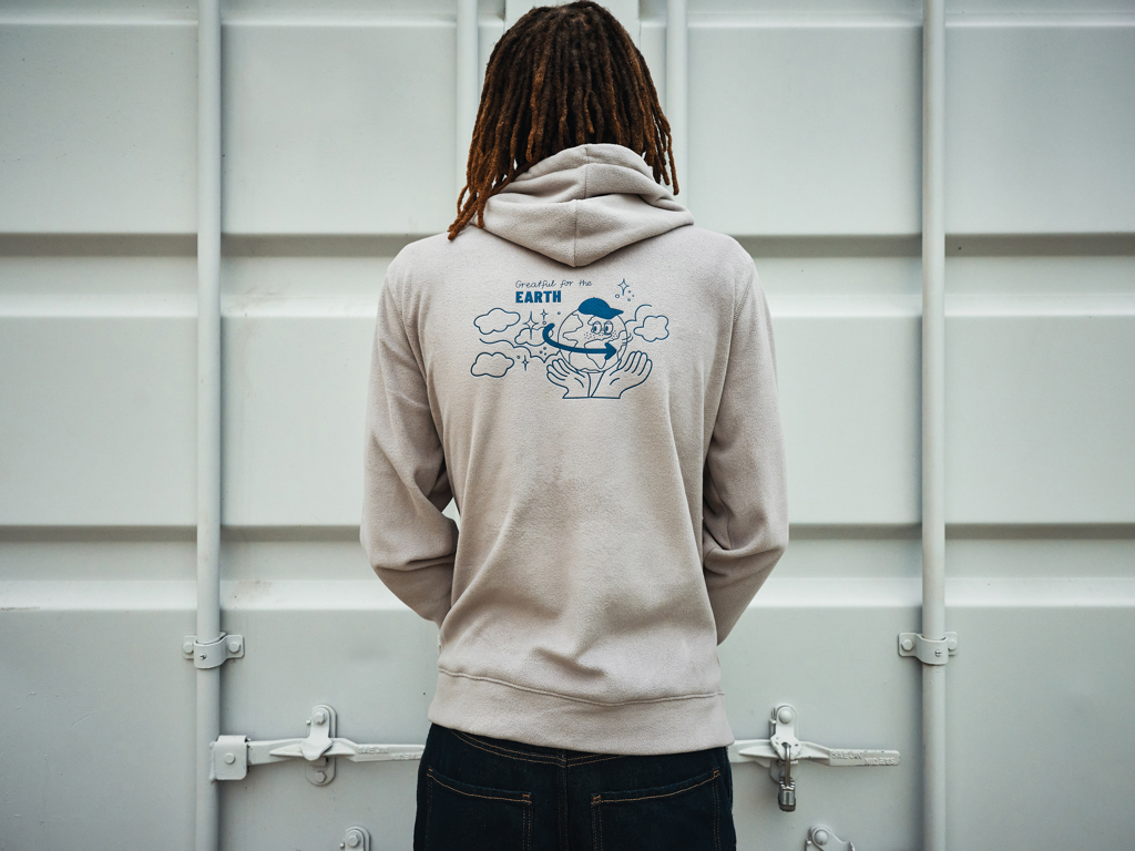 Personne portant un sweat à capuche beige illustré.