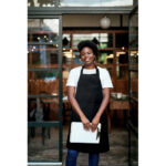 Serveuse souriante devant un restaurant moderne