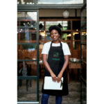 Serveuse souriante devant un restaurant végétarien.
