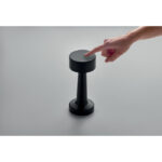 Doigt touchant une lampe noire moderne sur table grise