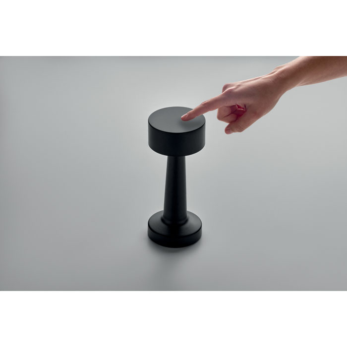 Doigt touchant une lampe noire moderne sur table grise