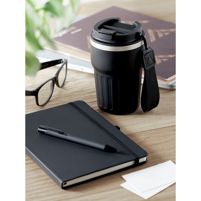 Tasse noire, carnet et stylo sur un bureau