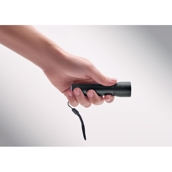 Main tenant une petite lampe de poche noire